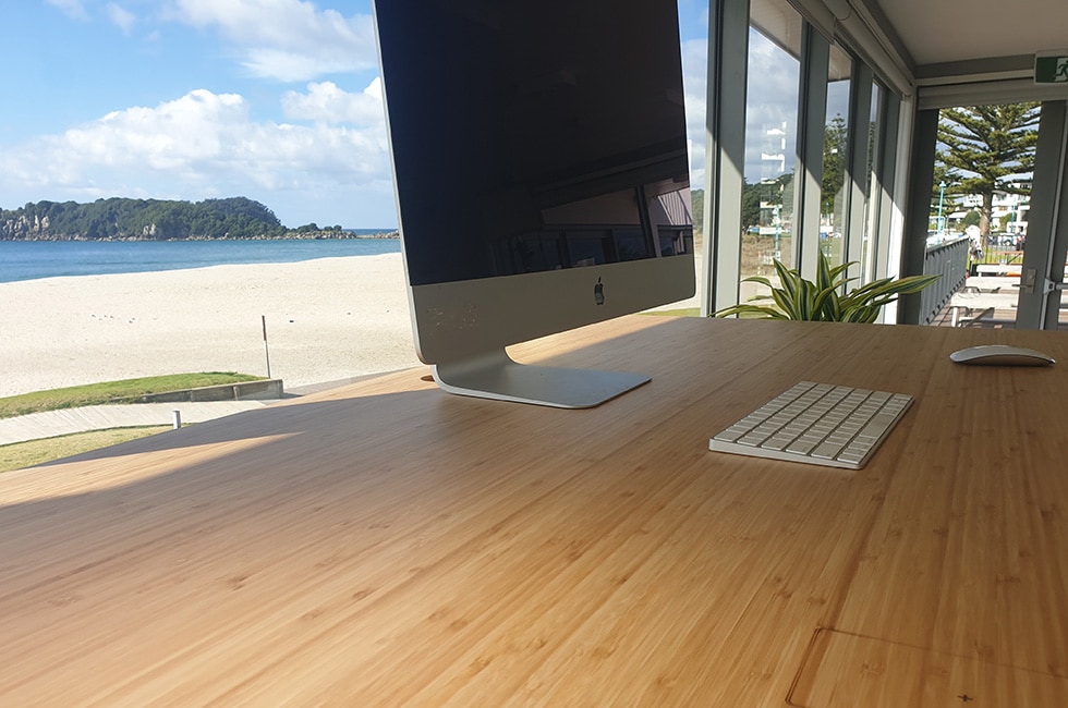 apple mac on bamboo desk with beach background