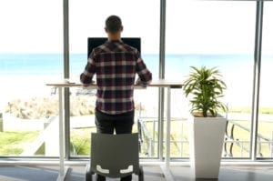 man in plaid shirt standing at desk with beach background