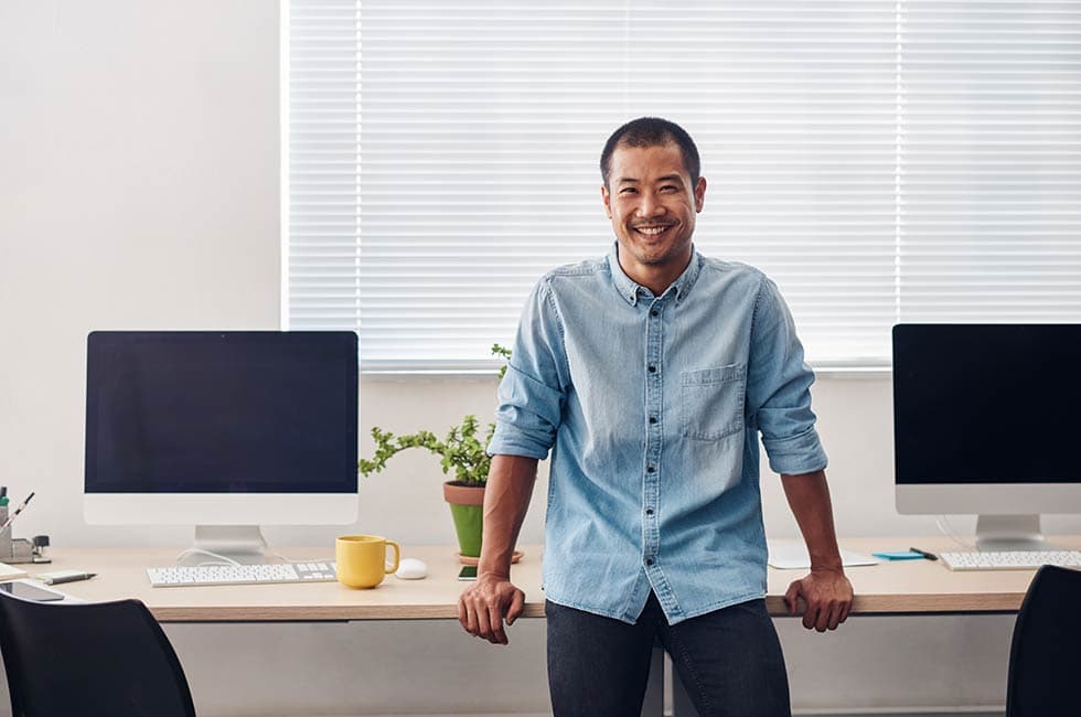 man in blue shirt sitting on an elevated standing desk